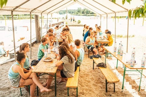 Mehrere Kids vom Camp sitzen am Tisch und essen.